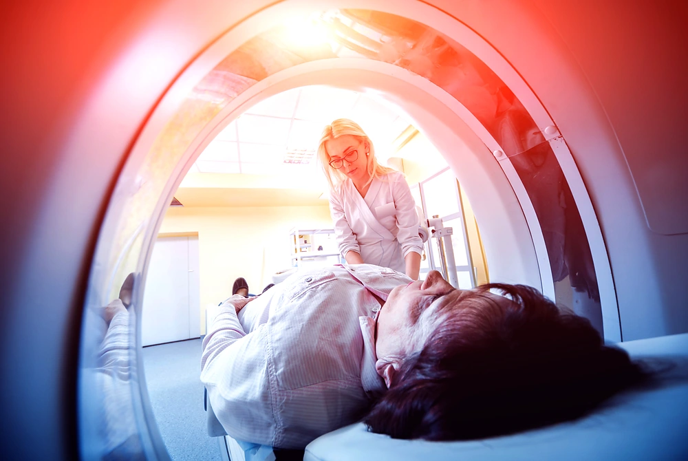 CT装置の中で検査を受ける患者と、体位を確認する医療従事者。