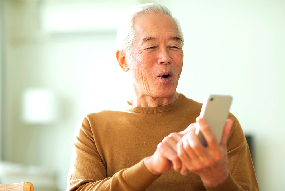 スマートフォンを見ながら操作する高齢男性。