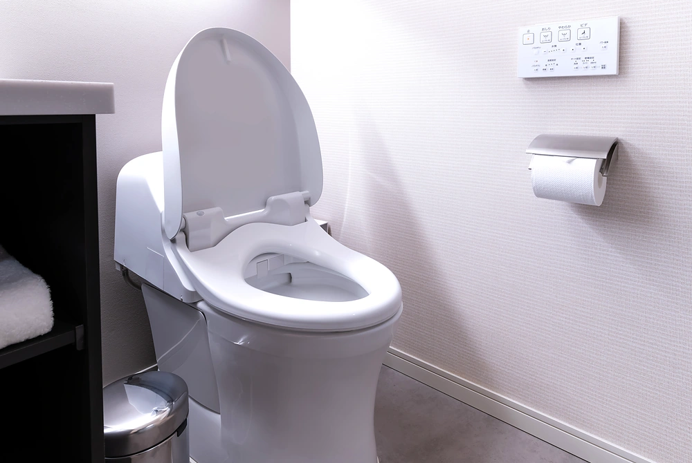 温水洗浄便座付きのトイレと操作パネルがある室内のトイレ空間。