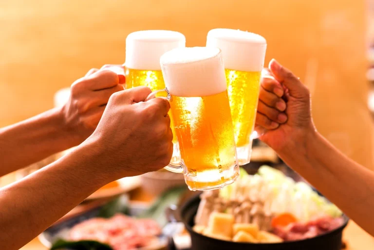 複数人がビールジョッキを持ち寄って乾杯している様子。
