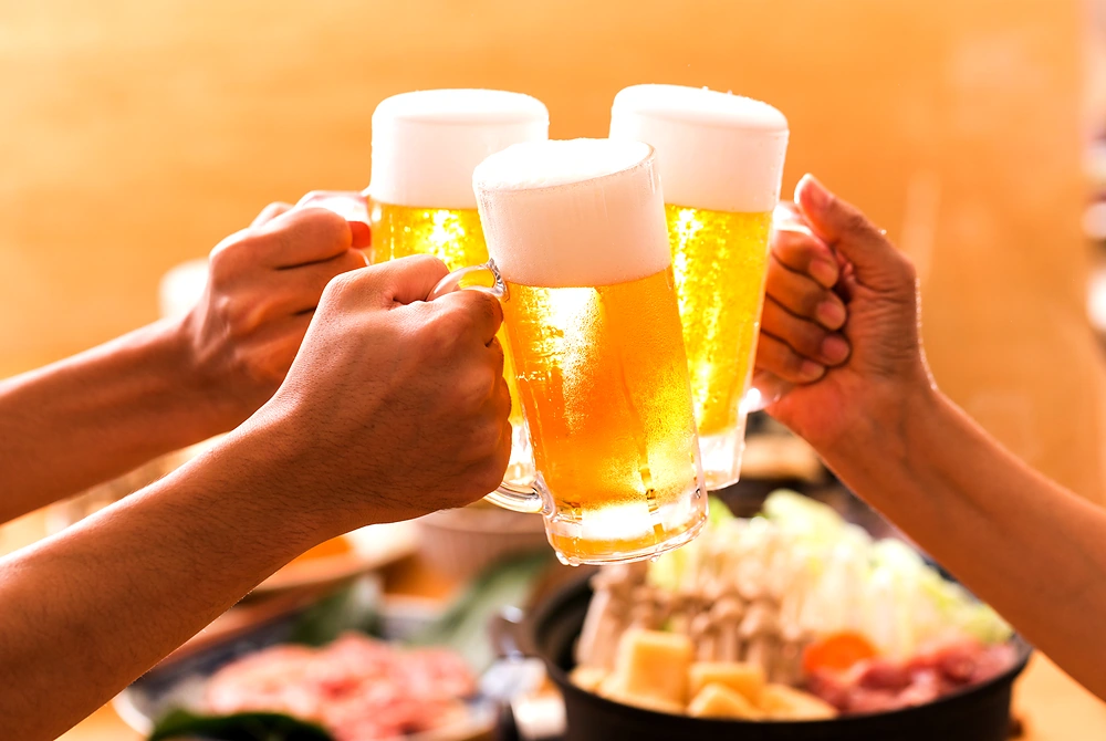 複数人がビールジョッキを持ち寄って乾杯している様子。