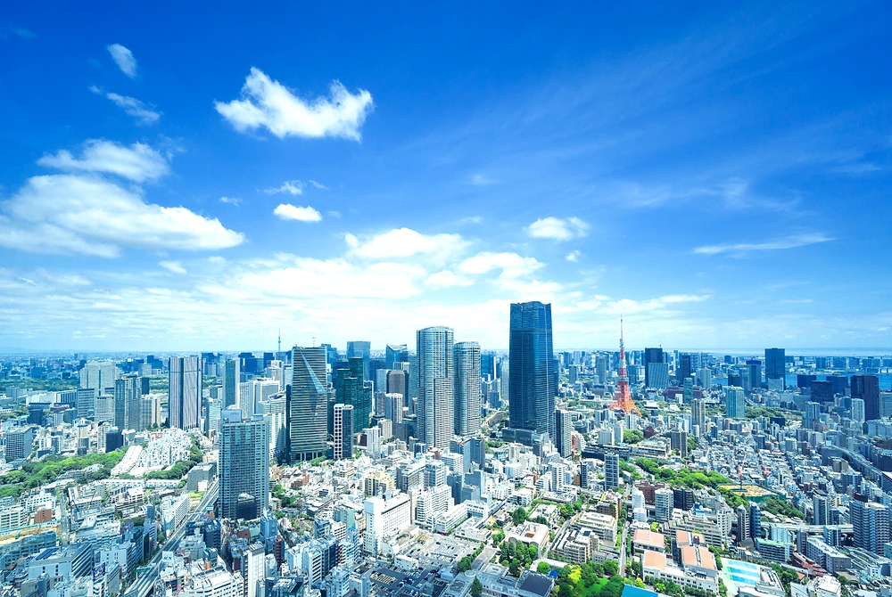 青空の下に広がる東京の高層ビル群と東京タワー。