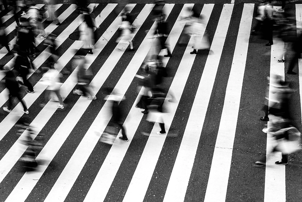 横断歩道を行き交う多くの人々を上から写したモノクロ写真。