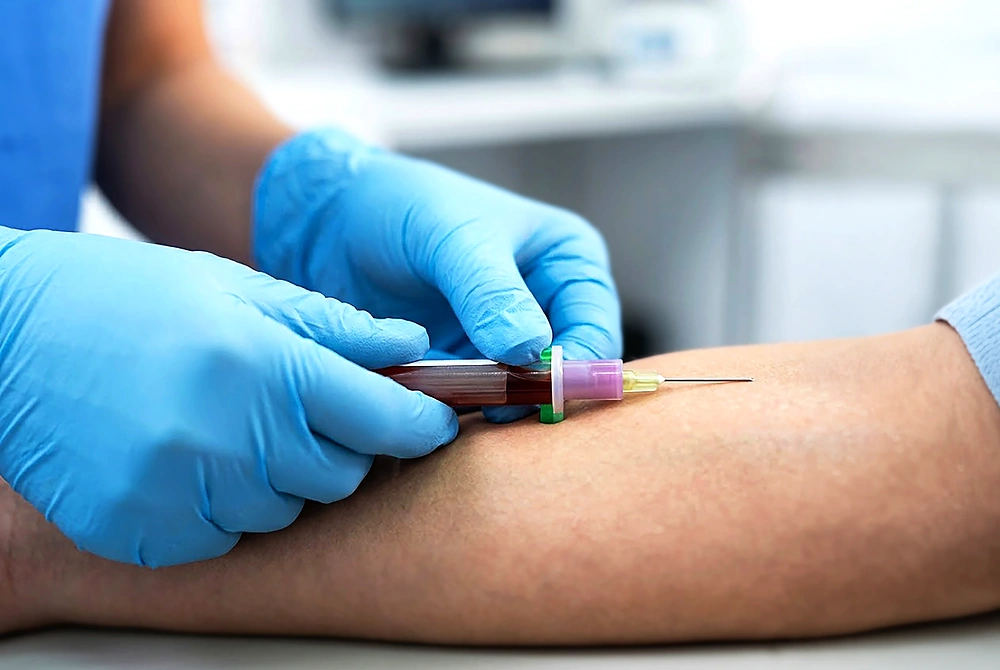 医療従事者が患者の腕から採血を行っている様子。