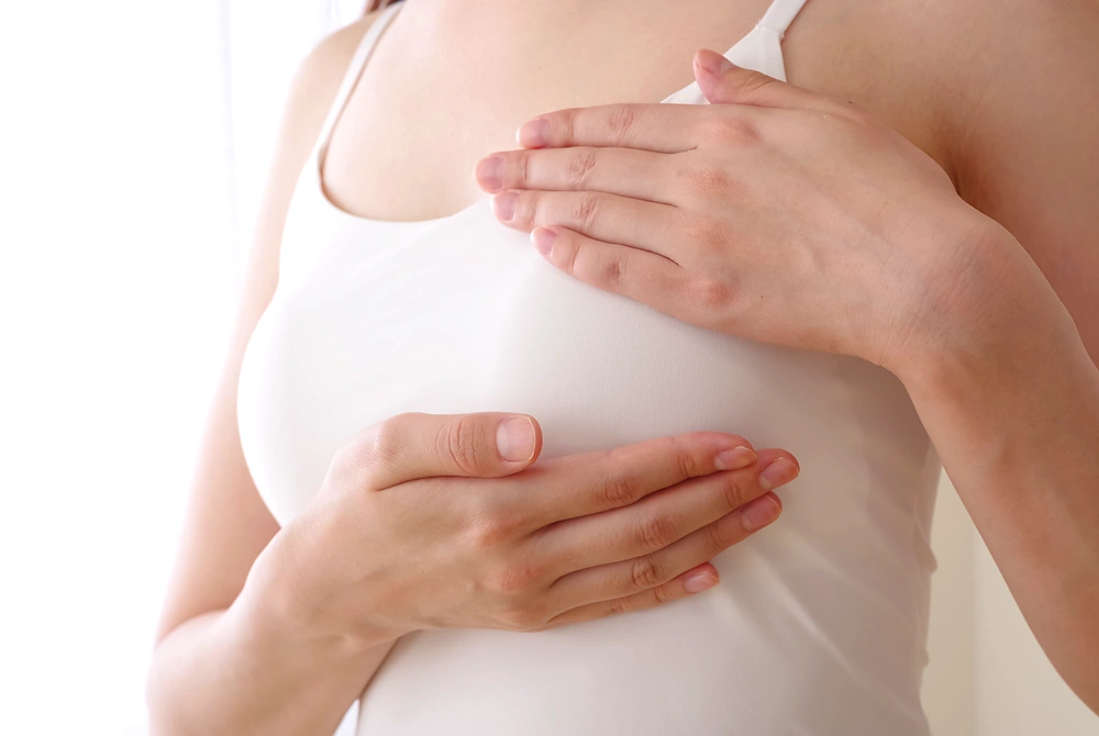 女性が衣服の上から乳房に手を当て、状態を確認している様子。