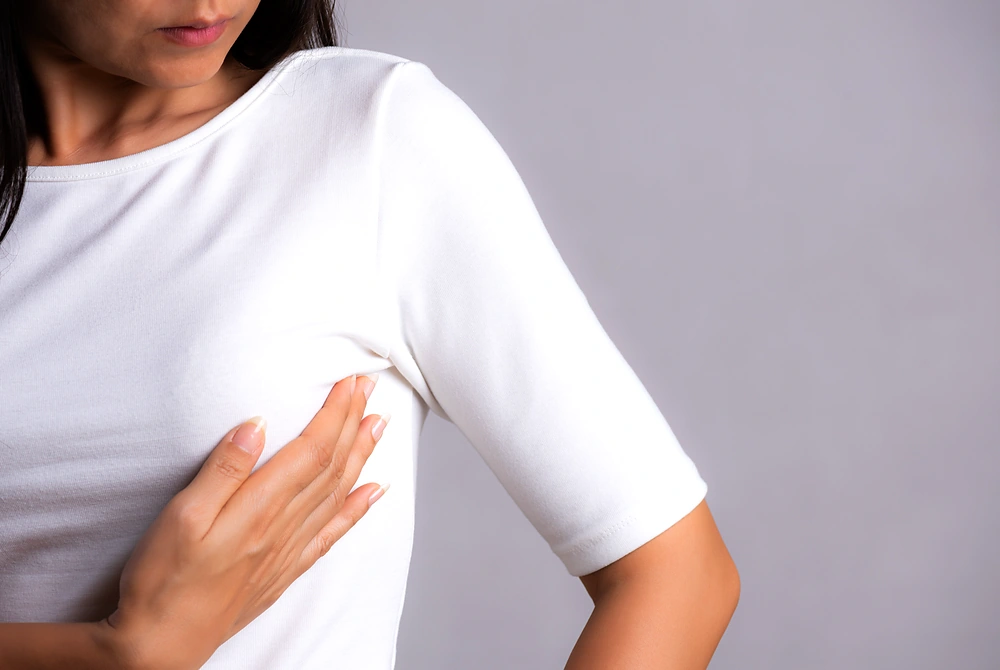 乳房に手を当ててセルフチェックをする女性の上半身。
