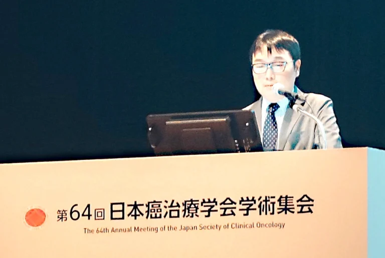 第64回日本癌治療学会学術集会の演台で、マイクを使って講演する坂東英明氏。
