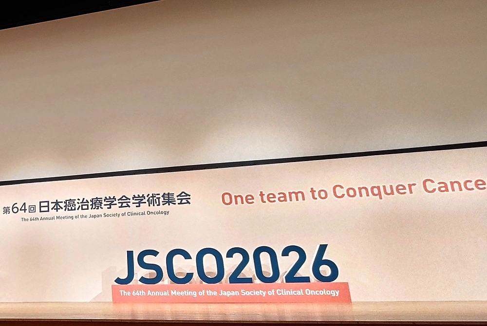 第64回日本癌治療学会学術集会の会場ステージ。大会テーマ「One team to Conquer Cancer」と「JSCO2026」の文字が掲げられている。