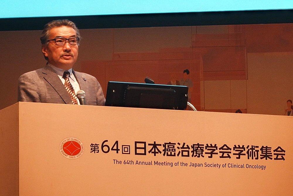 第64回日本癌治療学会学術集会の演台でマイクを持ち、睡眠に関する研究成果を紹介する筑波大学の柳沢正史氏。